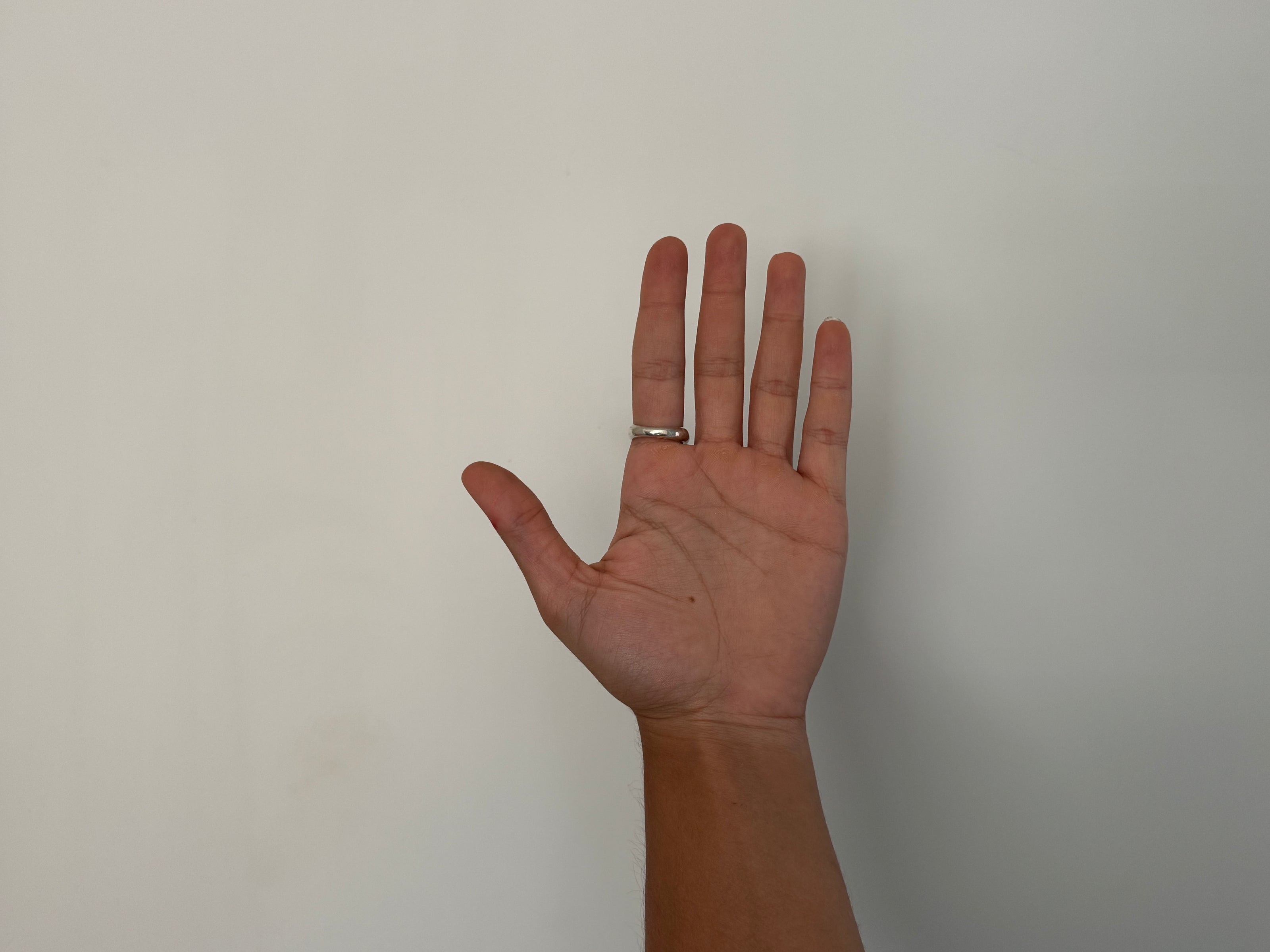 Hand with a ring on the index finger against a plain background